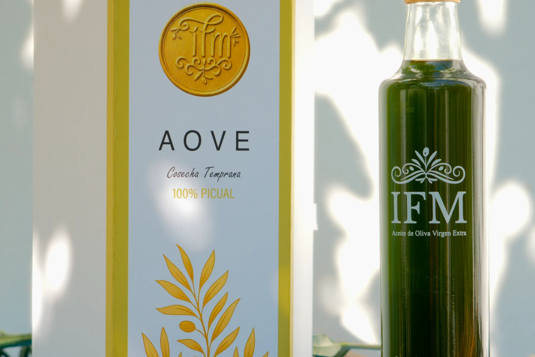 The IFM gift box next to the bottle, in the light through the leaves.