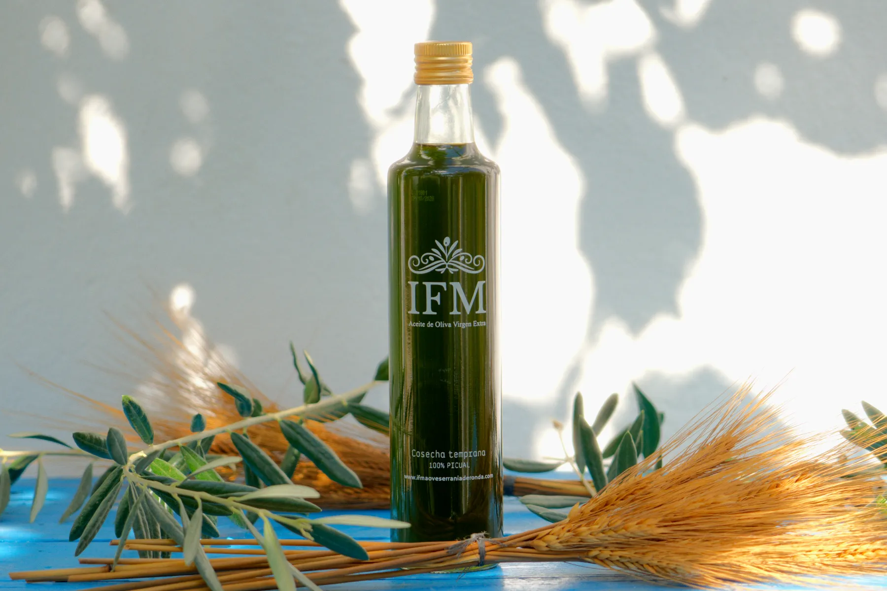 The IFM bottle among olive branches and ears of wheat.